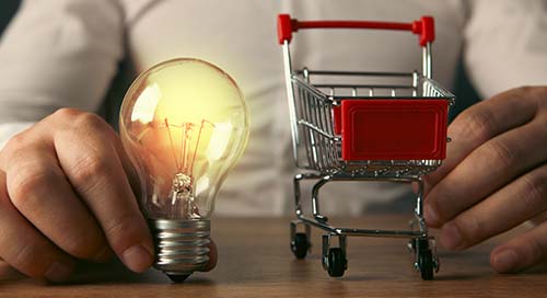 Hands holding lightbulb and small shopping card